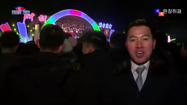 북한 인터넷 매체의 방송원이 지난해 12월 31일 김일성 광장에서 열린 새해맞이 공연 행사를 찾아 관객 속에서 방송을 진행하고 있다. 오른쪽 위 ‘현장취재’라는 글씨가 눈에 띈다.