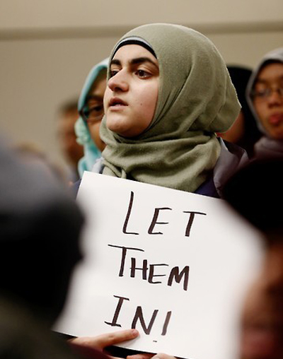 한 무슬림여성이 '그들을 들여보내라'라는 구호를 쓴 피켓을 들고 반이민 행정명령에 항의하고 있다. 