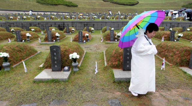 18일 오전 광주 북구 운정동 국립 5.18민주묘지에서 거행된 제30주년 5.18기념식이 끝난 뒤 한 유가족이 오색 우산을 쓴 채 묘역을 둘러보고 있다. 이날 기념식은 `임을 위한 행진곡'을 부르지 않는데 대해 5.18단체 회원들이 행사장에 진입, 항의하는 등 마찰을 겪었다.