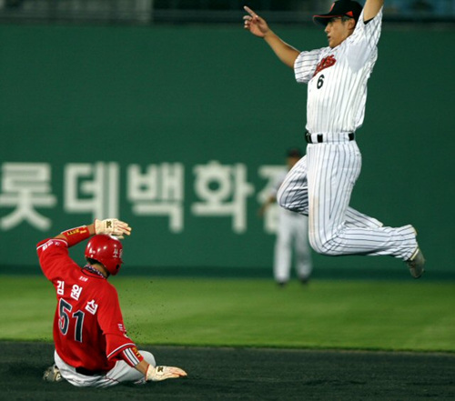 27일 부산 사직야구장에서 열린 프로야구 롯데-기아 경기에서 5회초 1사 1,3루 상황에서 1루주자 김원섭이 도루를 성공시키고 있다. 롯데 유격수 황재균이 강민호의 높은 송구를 받기 위해 뛰어 올랐다.