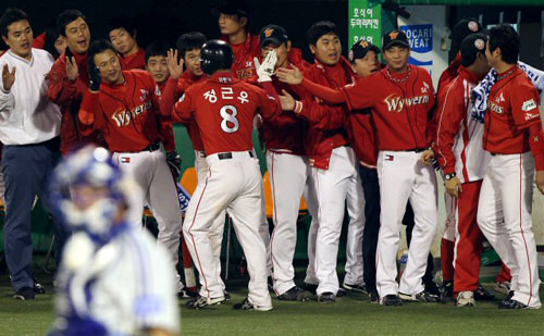 19일 대구 시민운동장에서 열린 프로야구 한국시리즈 4차전 삼성-SK 경기 4회초 1사 만루, SK 박경완의 타석 때 밀어내기로 홈인한 정근우가 동료들의 축하를 받고 있다.