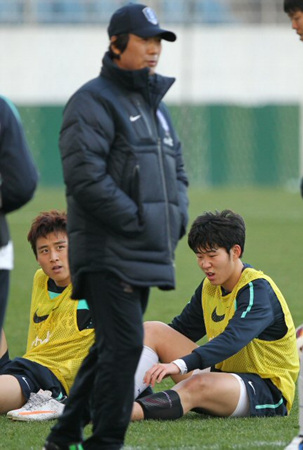 22일 오후 제주월드컵경기장에서 축구 국가대표팀의 훈련이 끝난 가운데 구자철과 손흥민이 신발을 벗고 쉬고 있는 앞으로 조광래 감독이 지나가고 있다.