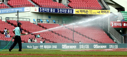 야구장이 때아닌 '석면 파동'에 휩싸이면서 운동장 관리요원들이 석면이 날리는 것을 막으려고 28일 오후 서울 잠실야구장에서 물을 뿌리고 있다. 관리요원들은 양팀 선수들의 훈련 전과 경기 시작 전에 고무호스를 이용해 운동장에 물을 듬뿍 뿌렸다.