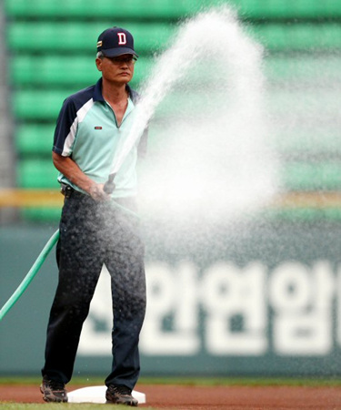 야구장이 때아닌 '석면 파동'에 휩싸이면서 운동장 관리요원들이 석면이 날리는 것을 막으려고 28일 오후 서울 잠실야구장에서 물을 뿌리고 있다. 관리요원들은 양팀 선수들의 훈련 전과 경기 시작 전에 고무호스를 이용해 운동장에 물을 듬뿍 뿌렸다.