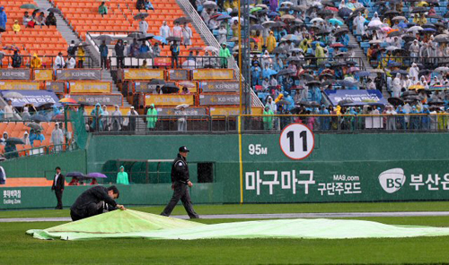 22일 부산 사직야구장에서 열릴 예정이었던 2011 프로야구 플레이오프 5차전 롯데 자이언츠-SK 와이번스 경기가 비로 취소됐다. 경기 관계자들이 취소 직전 그라운드 상태를 살피고 있다.