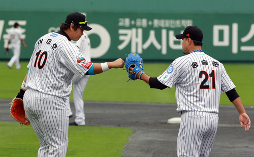 23일 부산 사직야구장에서 열린 2011 프로야구 플레이오프 5차전 롯데 자이언츠와 SK 와이번스의 경기. 1회초 SK 박재상을 아웃시킨 이대호와 투수 송승준이 주먹을 맞대고 있다.