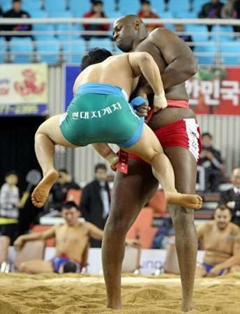 24일 경북 김천실내체육관에서 열린 2011 천하장사 씨름대축제의 세계씨름친선교류전에 참가한 금강급(90kg 이하)의 안태민(현대삼호)이 신장 230cm, 체중 170kg의 '골리앗' 커티스 존슨(미국)의 공격을 받자 몸에 바짝 붙어 매달린 채 버티고 있다.