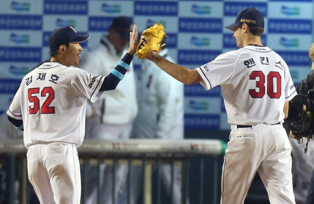 28일 오후 잠실구장에서 열린 프로야구 한국시리즈 4차전 두산 대 삼성 경기. 7회초 삼성의 공격을 무사히 막은 두산 투수 핸킨스가 덕아웃으로 들어가며 김재호와 하이파이브를 하고 있다.