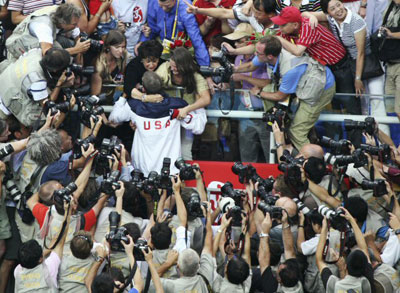 17일 오전 중국 베이징 국가아쿠아틱센터에서 열린 2008 베이징올림픽 수영 남자 혼계영 400m에서 금메달을 추가해 8관왕을 차지한 ‘수영 황제’ 마이클 펠프스(오른쪽)가 시상식을 마친 후 어머니 데보라(왼쪽)와 누나 힐러리(가운데)에게 다가가 함께 기쁨하는 가운데 수많은 취재진이 촬영을 하고 있다. 