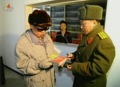  북한 김정일 국방위원장이 헌법절을 맞아 조선인민군 제 323 군부대 지휘부를 방문 중 오른손으로 책을 들어 살펴보는 모습. 
