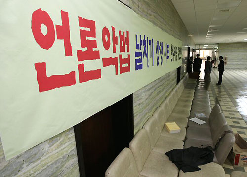  한나라당의 미디어법 상정이 이뤄진 국회 문방위 회의실 앞에서 밤을 지샌 당직자들이 26일 한나라당을 규탄하는 대형 플래카드 앞에서 침구를 정리하고 있다. 민주당은 한나라당의 미디어법 본회의 상정을 위한 표결을 막기위해 문방위 회의실에서 의원총회를 지속적으로 열 예정이다. 
