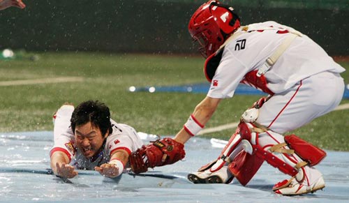 9일 광주 무등 야구장에서 열릴 예정이었던 2009 프로야구 KIA 타이거즈-LG 트윈스 경기가 우천으로 취소되자 KIA 신인 안치홍(왼쪽)이 빗속에서 슬라이딩을 하며 경기장을 찾은 팬들을 위한 세리머니를 선보이고 있다. 