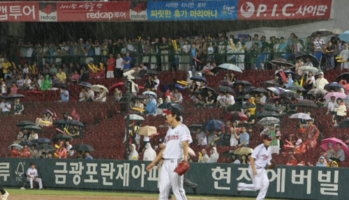 장맛비가 내린 6일 잠실야구장에서 벌어진 프로야구 KIA-LG전 7회초에 관중들이 처마밑에 모여 우중경기를 관전하고 있다. 