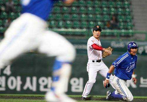  22일 인천 문학구장에서 열린 2009 프로야구 SK 와이번스-삼성 라이온즈 경기, SK 2루수 정근우(가운데)가 삼성 1루 주자 채태인(오른쪽)을 포스아웃 시킨 후 타자 현재윤까지 아웃시키기 위해 1루로 송구하고 있다. 