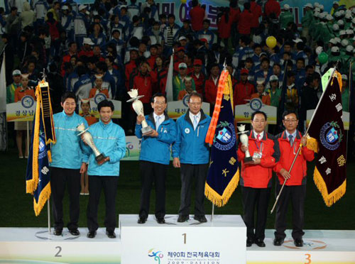  제90회 대전 전국체전에서 종합 1위를 차지한 경기도(가운데) , 2위 서울(왼쪽), 3위 대전선수단 대표가 26일 대전월드컵경기장에서 열린 폐막식에서 우승 트로피를 받고 기뻐하고 있다. 